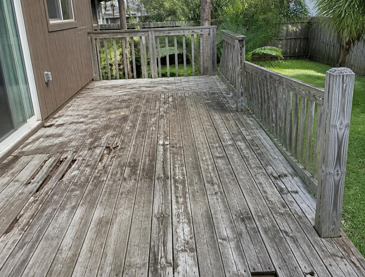 Weathered wood deck with rotted boards and loose railing before repair